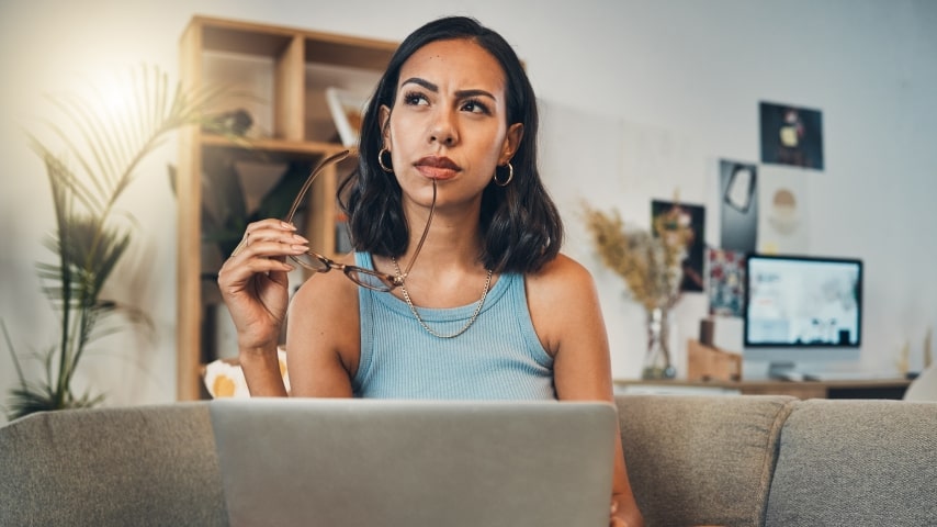 Pros and Cons of Selling Art With Shopify A woman working on a laptop and thinking.