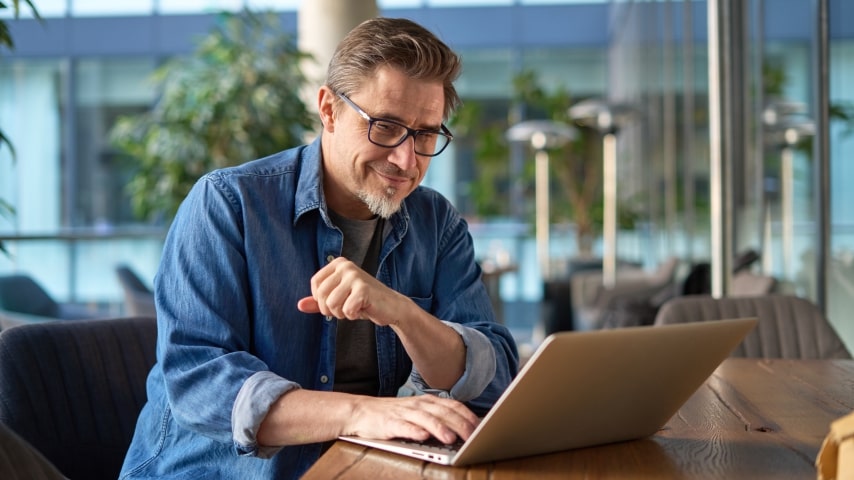 Tips to Successfully Sell Art on Shopify A man looking at a laptop screen and smiling.